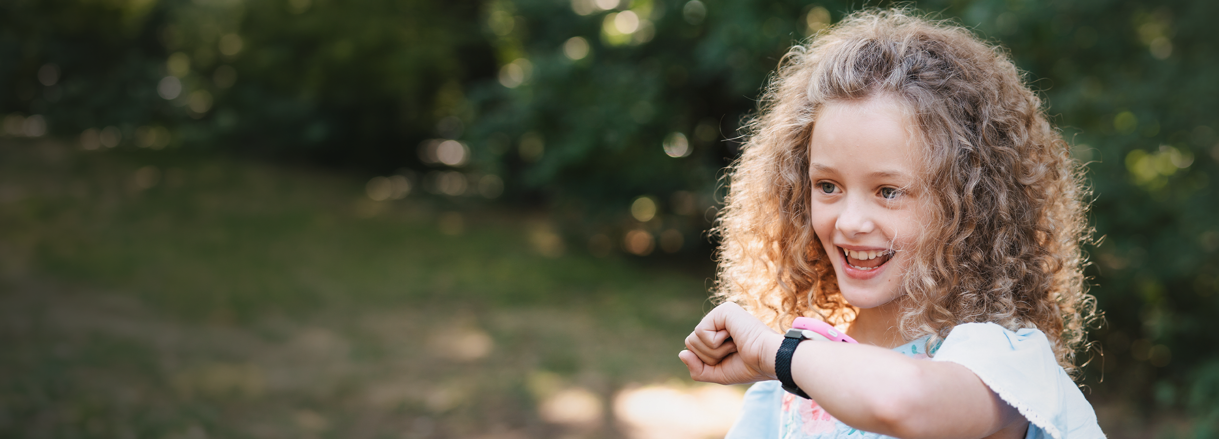 Young girl with curly hair smiling outdoors